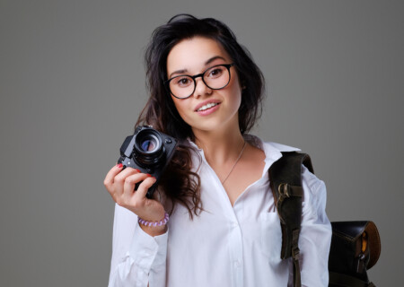 positive-female-tourist-with-photo-camera-travel-backpack