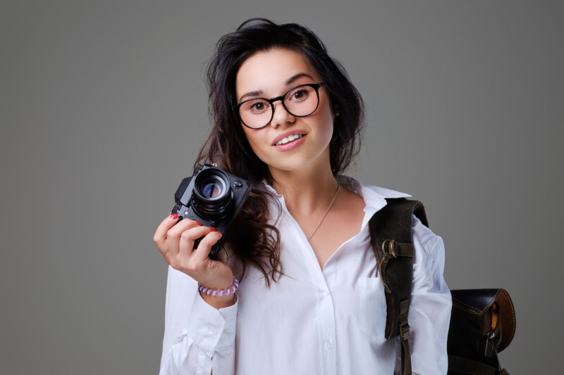positive-female-tourist-with-photo-camera-travel-backpack