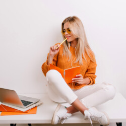 glad-fair-haired-woman-trendy-outfit-doing-her-job-office-holding-notebook-pen